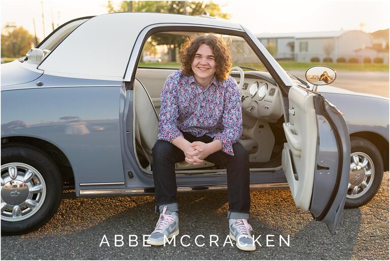 Senior portrait sitting in Charlotte the Figgy, a 1991 Nissan Figaro