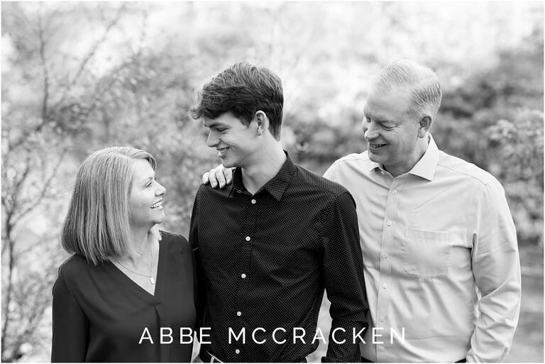 Black and white candid family portrait of a high school senior boy and his parents