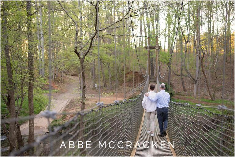 Father and a graduating son walking across the swinging bridge at Anne Springs Close Greenway in Fort Mill, SC