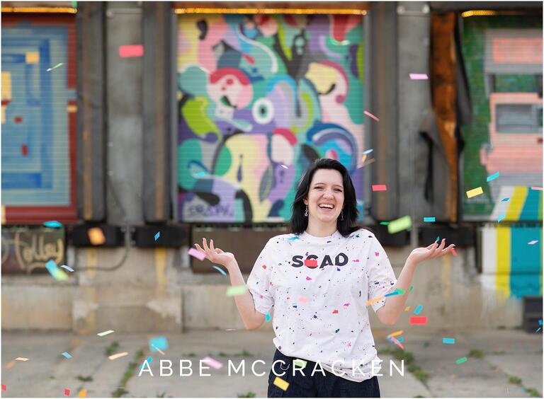Senior picture of a girl wearing her new college tee shirt being showered with confetti