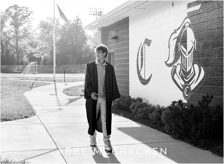 Senior scholar athlete in graduation gown near Guy Field on the campus of Charlotte Christian