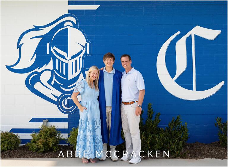 Senior portrait with parents on a themed blue and white wall at Charlotte Christian