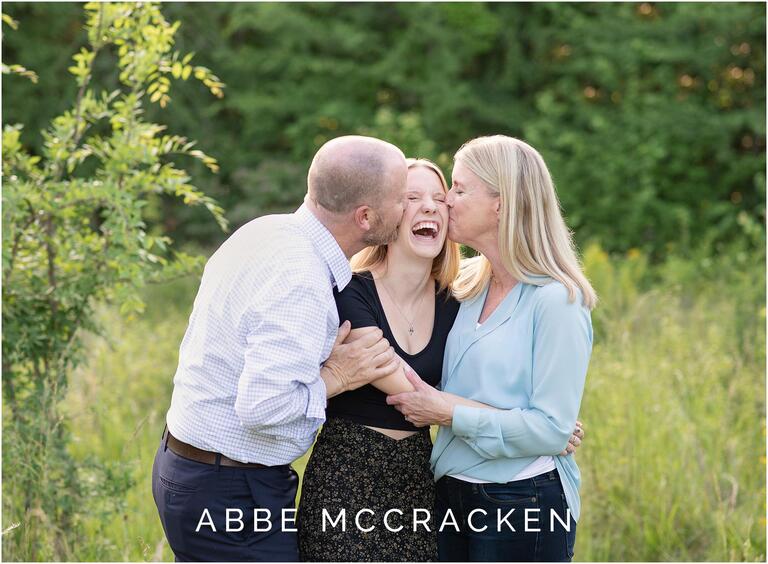 Image of mom and dad kissing the cheeks of their high school senior
