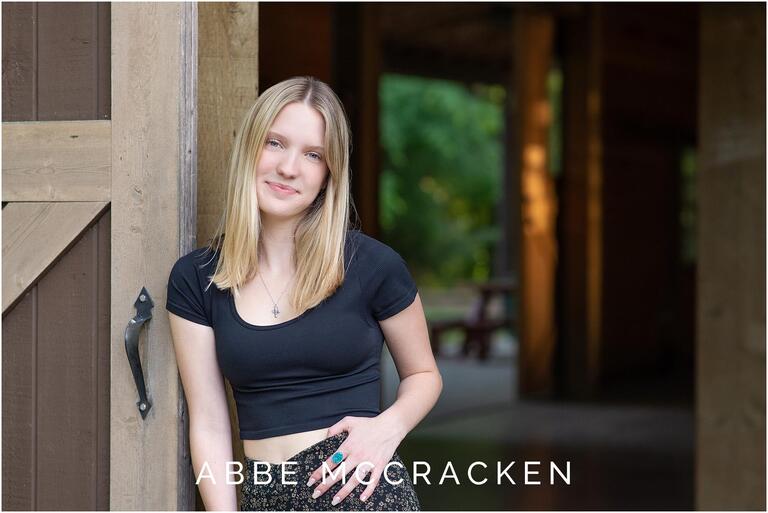 Picture of a blonde girl leaning on a barn door in Charlotte, NC