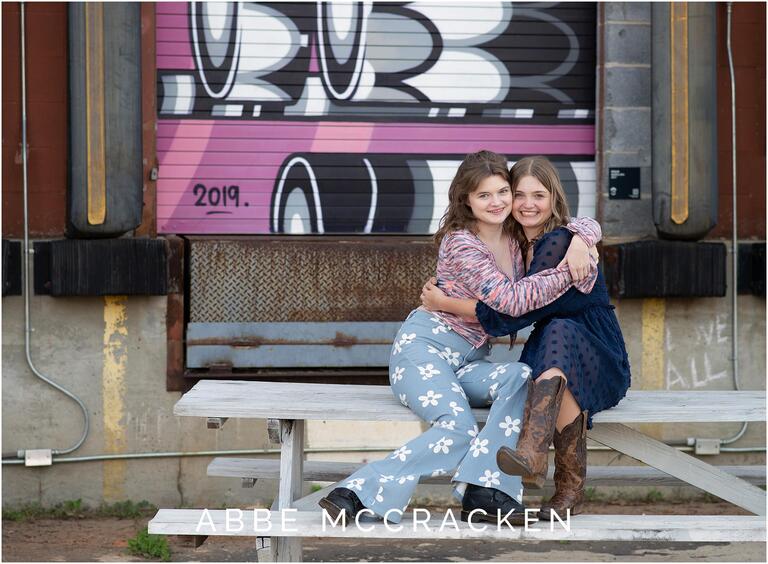 Sisters sitting on a picnic table hugging