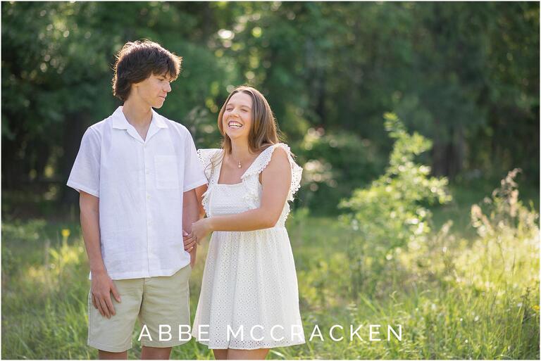 Candid of siblings laughing in a natural wheat field, backlit