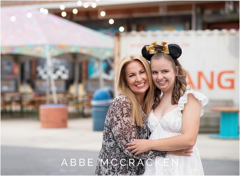 Senior girl wearing 2023 Mickey Mouse graduation ears hugging her mom