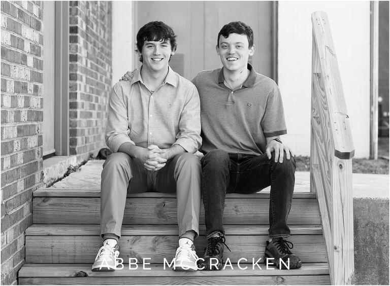 Brothers sit on wooden steps during senior portraits