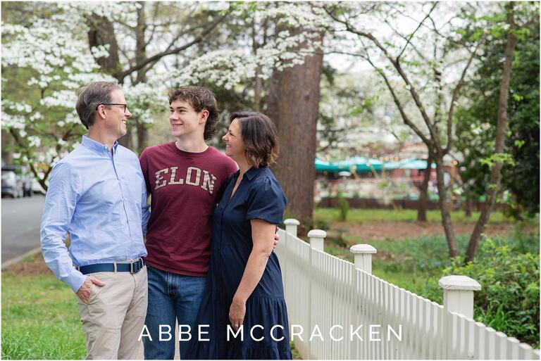 Candid senior photo with parents, dogwood blooms in background