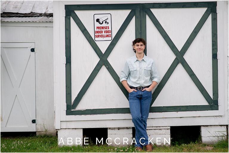 Portrait of a teenage boy leaning on white and green doors behind Matthews Community Farmers Market