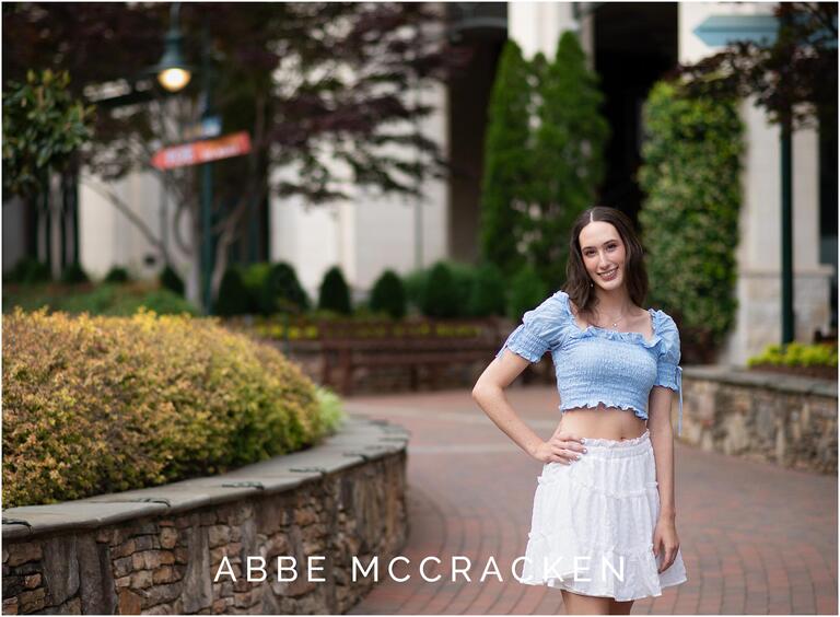 Senior portrait of a girl standing on the brick-lined walkway of The Green in Uptown Charlotte