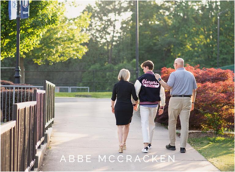 Senior boy and family walk on Providence Day School campus during spring senior session