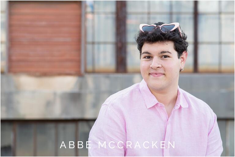 high school senior wearing pink linen shirt and pink heart sunglasses in senior portrait