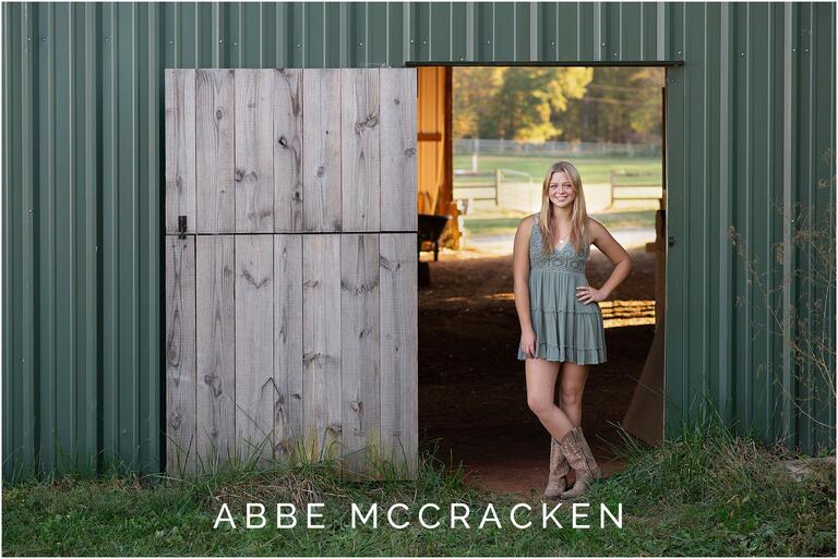 Senior portrait of a girl standing in door of a green barn