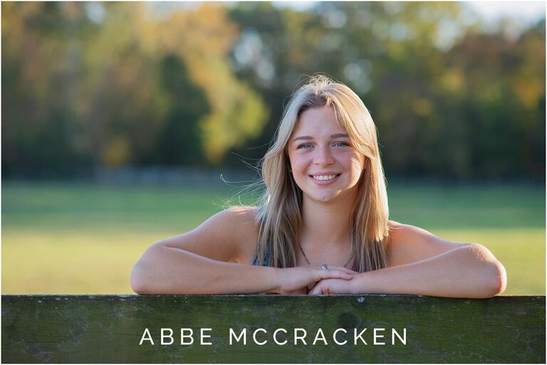 Senior portrait leaning on a wooden farm fence