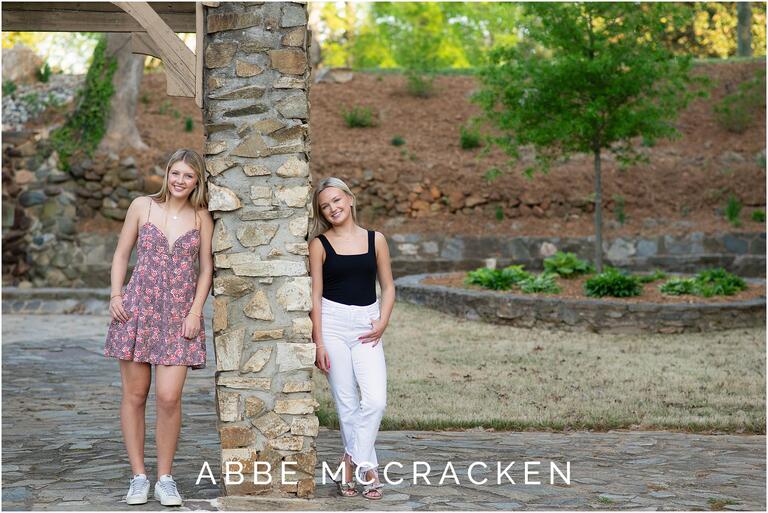 Portrait of two high school seniors who are best friends leaning on a stone column in Independence Park