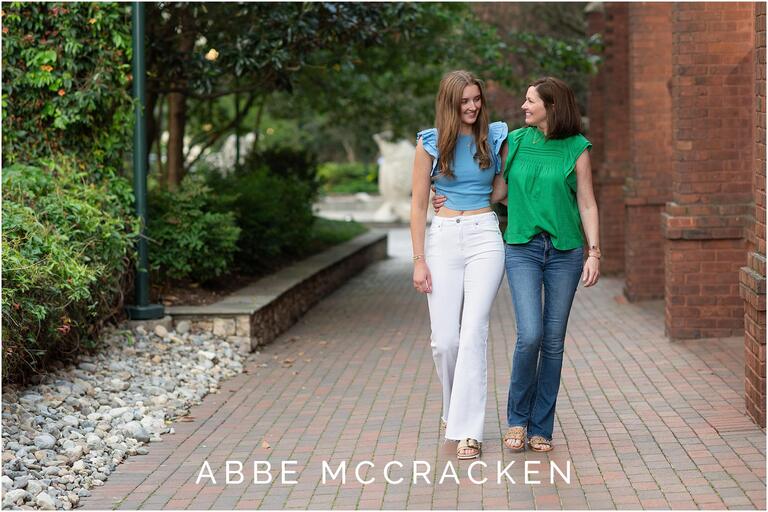 senior portrait of a mother and daughter walking with arms around each other
