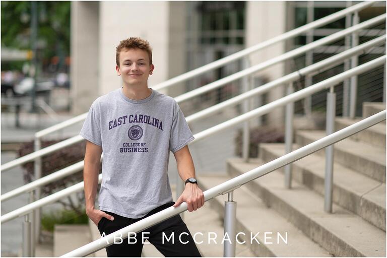 Senior portrait wearing college t shirt, photographed on the steps of the Mint Museum