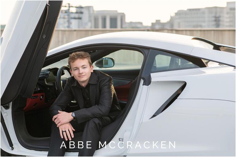 High school senior portrait sitting in white sports car