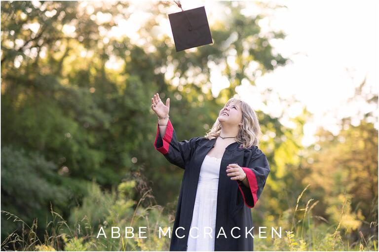 Candid image of senior in graduation gown tossing her cap in the air